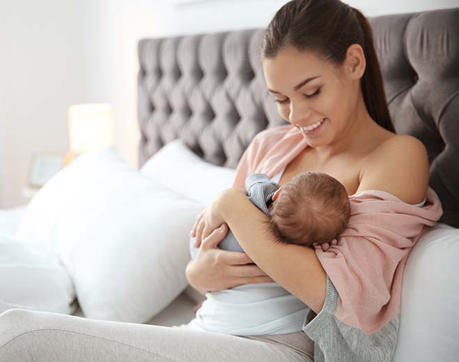 Parent holding and feeding newborn baby