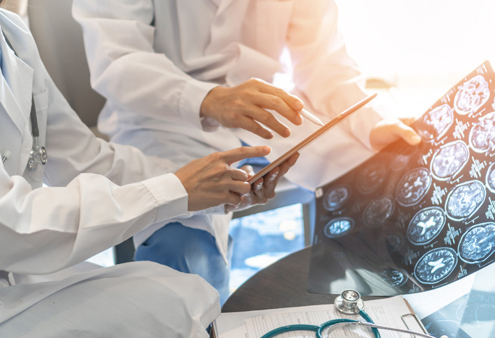 Clinicians reviewing brain scans and digital tablet